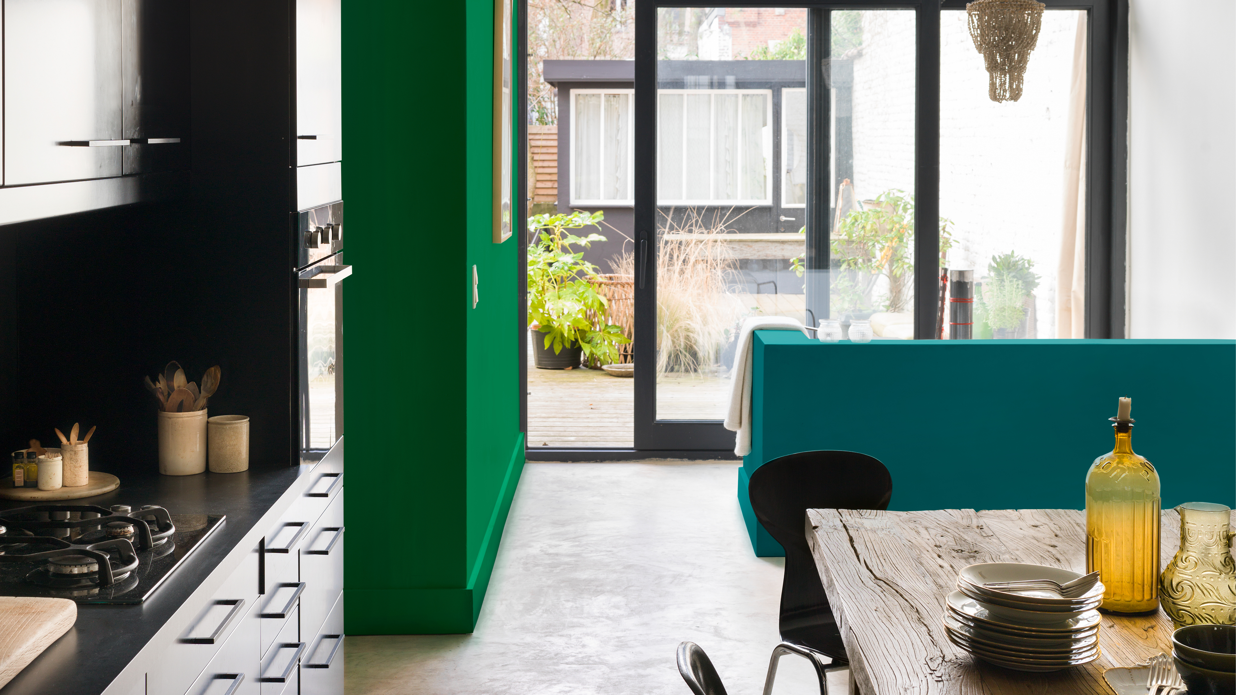 Open-plan kitchen with green wall The easiest way to create a harmonious open-plan scheme is to pick one or two colours and use different tones of these colours throughout the entire scheme.